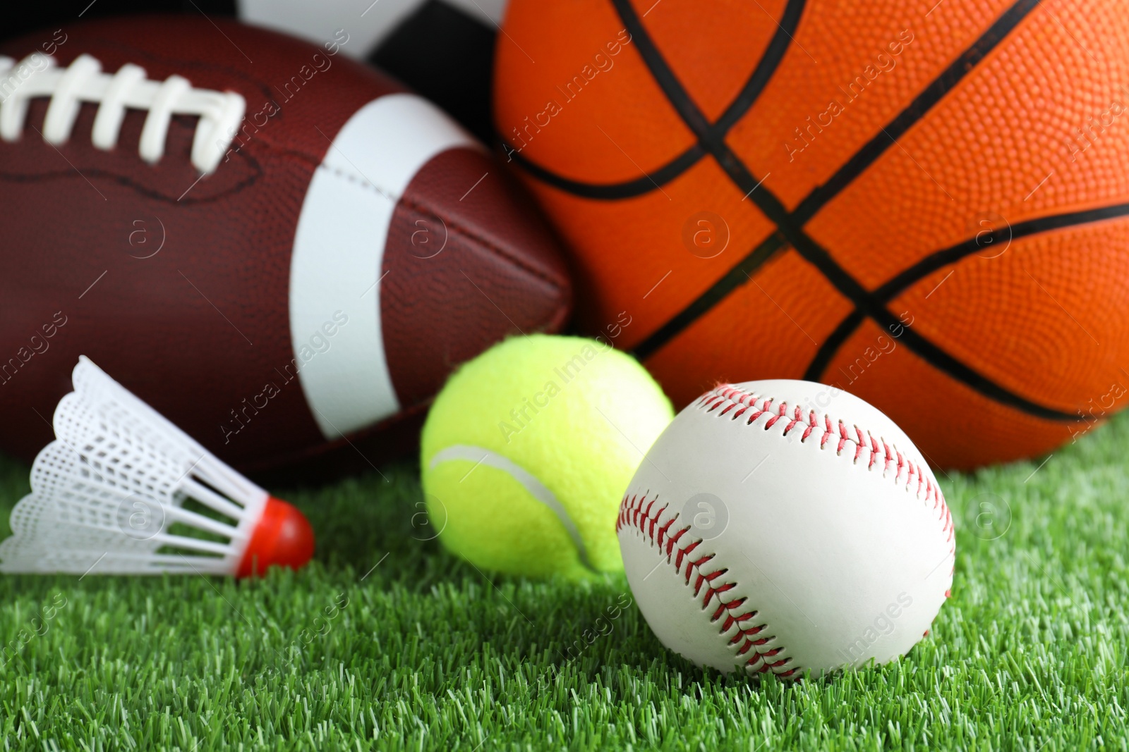 Photo of Set of different sport balls and shuttlecock on green grass, closeup