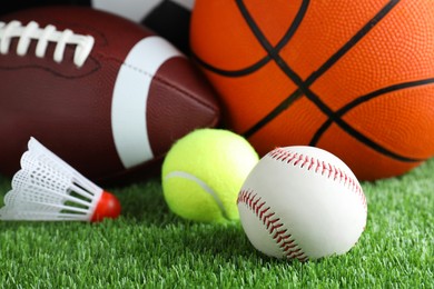 Photo of Set of different sport balls and shuttlecock on green grass, closeup