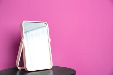 Stylish mirror on table near color wall Photo of Stylish mirror on table near color wall