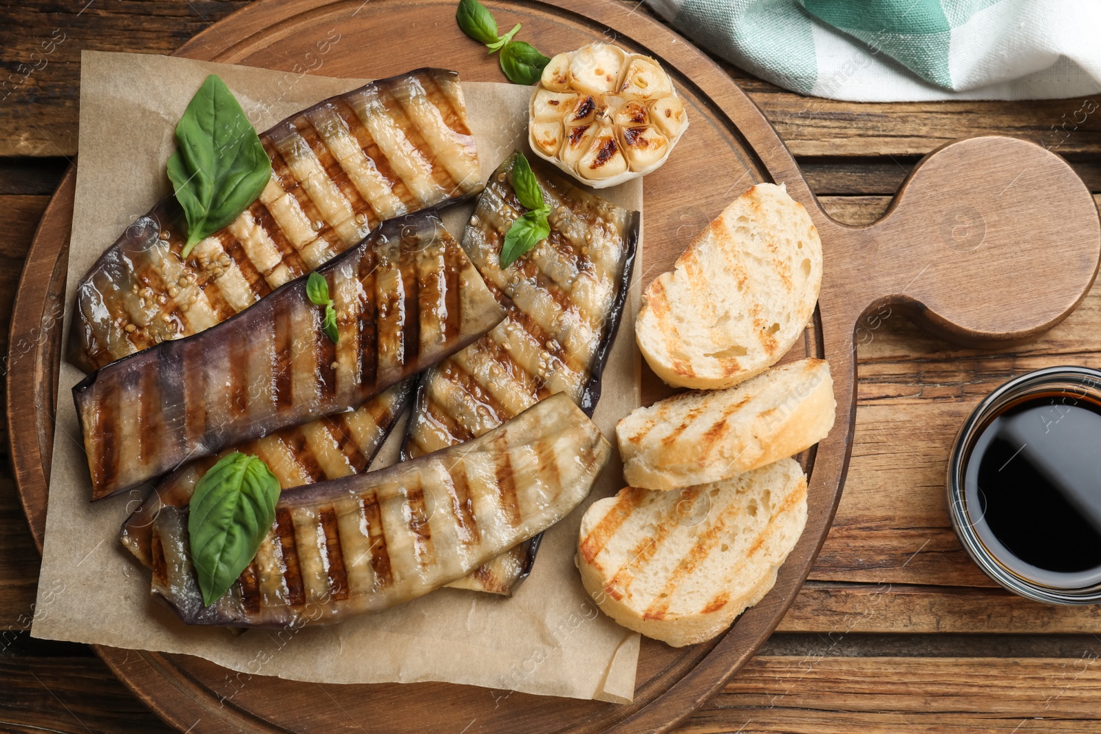 Delicious grilled eggplant slices served on wooden table, flat lay Photo of Delicious grilled eggplant slices served on wooden table, flat lay