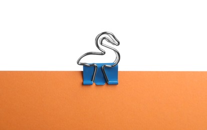 Orange paper with bird shaped binder clip isolated on white Photo of Orange paper with bird shaped binder clip isolated on white
