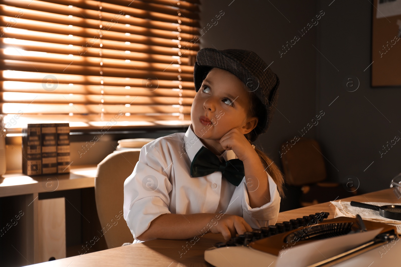 Cute little detective using typewriter at table in office Photo of Cute little detective using typewriter at table in office