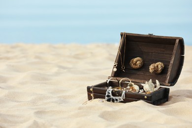 Open wooden chest with treasures on sandy beach, space for text Photo of Open wooden chest with treasures on sandy beach, space for text