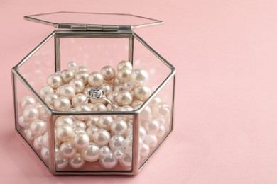 Glass box with decor pearls and engagement ring on pink background, space for text Photo of Glass box with decor pearls and engagement ring on pink background, space for text