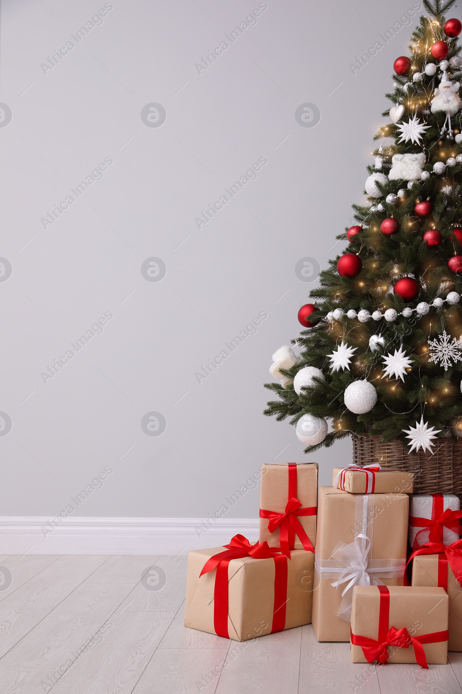 Christmas tree and gift boxes near light grey wall, space for text Photo of Christmas tree and gift boxes near light grey wall, space for text