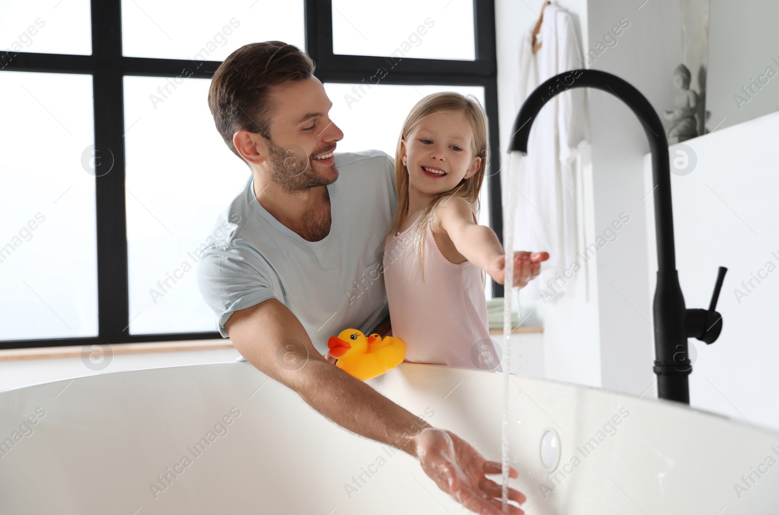 Father with his cute little daughter filling tub in bathroom Photo of Father with his cute little daughter filling tub in bathroom