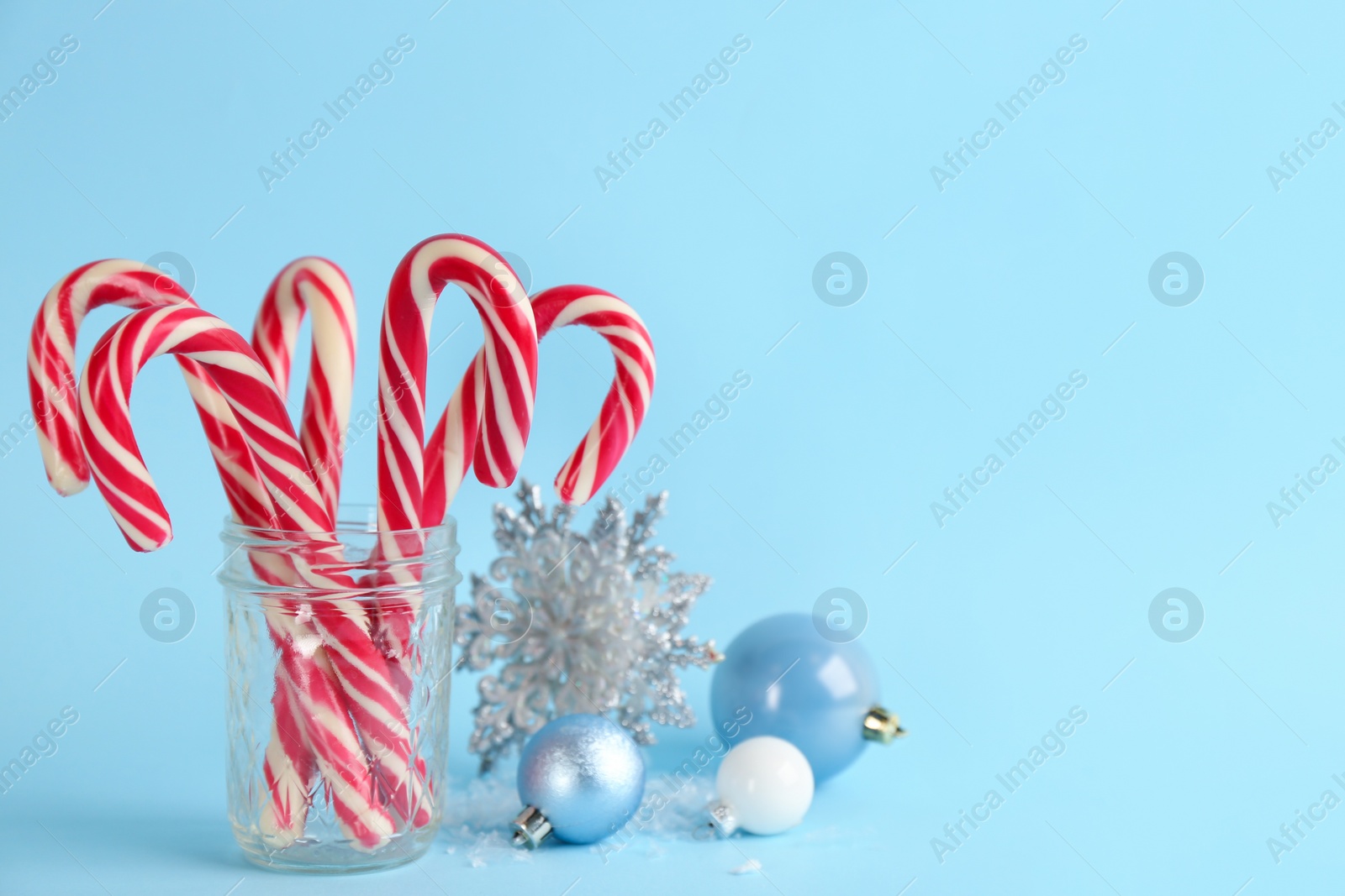 Candy canes and Christmas decor on light blue background, space for text Photo of Candy canes and Christmas decor on light blue background, space for text
