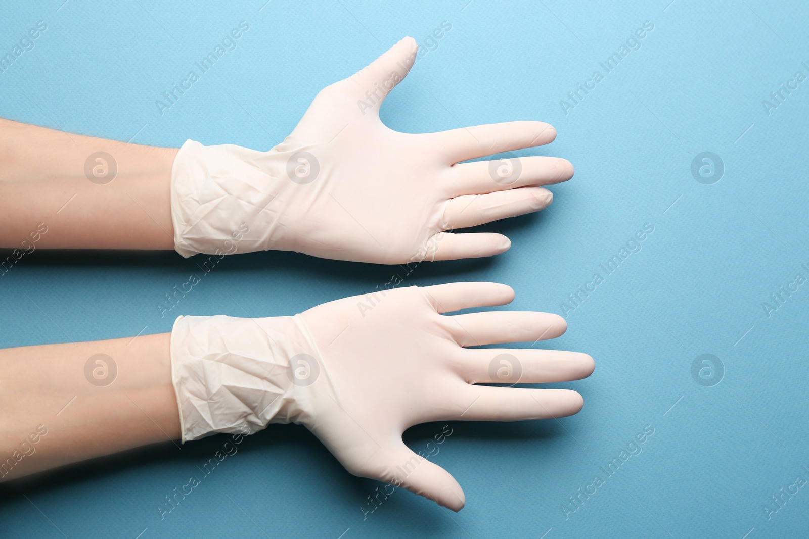 Person in medical gloves on blue background, closeup of hands Photo of Person in medical gloves on blue background, closeup of hands