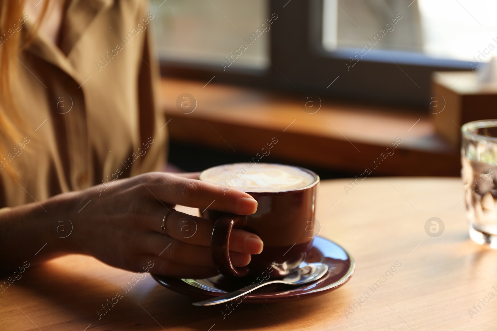 Photo of Woman with aromatic coffee at table in cafe, closeup