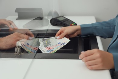 Woman giving money to cashier in bank, closeup. Currency exchange Photo of Woman giving money to cashier in bank, closeup. Currency exchange