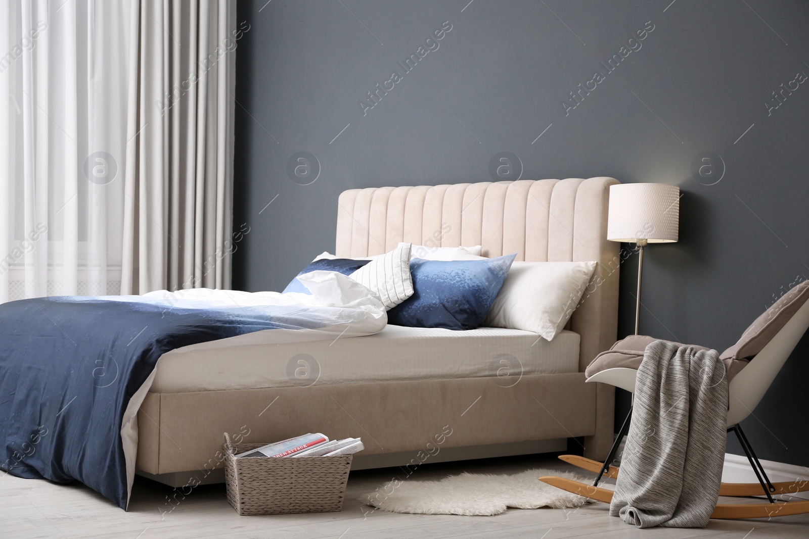 Comfortable bed with pillows and soft blanket in room. Stylish interior design Photo of Comfortable bed with pillows and soft blanket in room. Stylish interior design