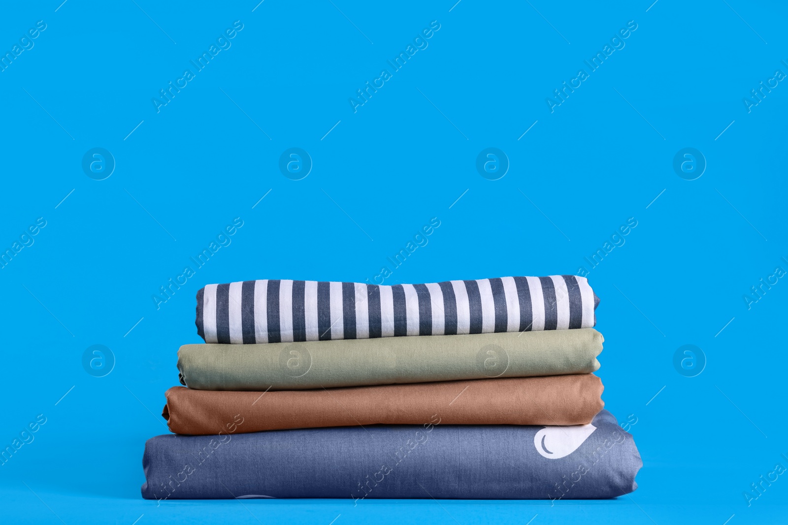 Stack of clean bed sheets on blue background Photo of Stack of clean bed sheets on blue background