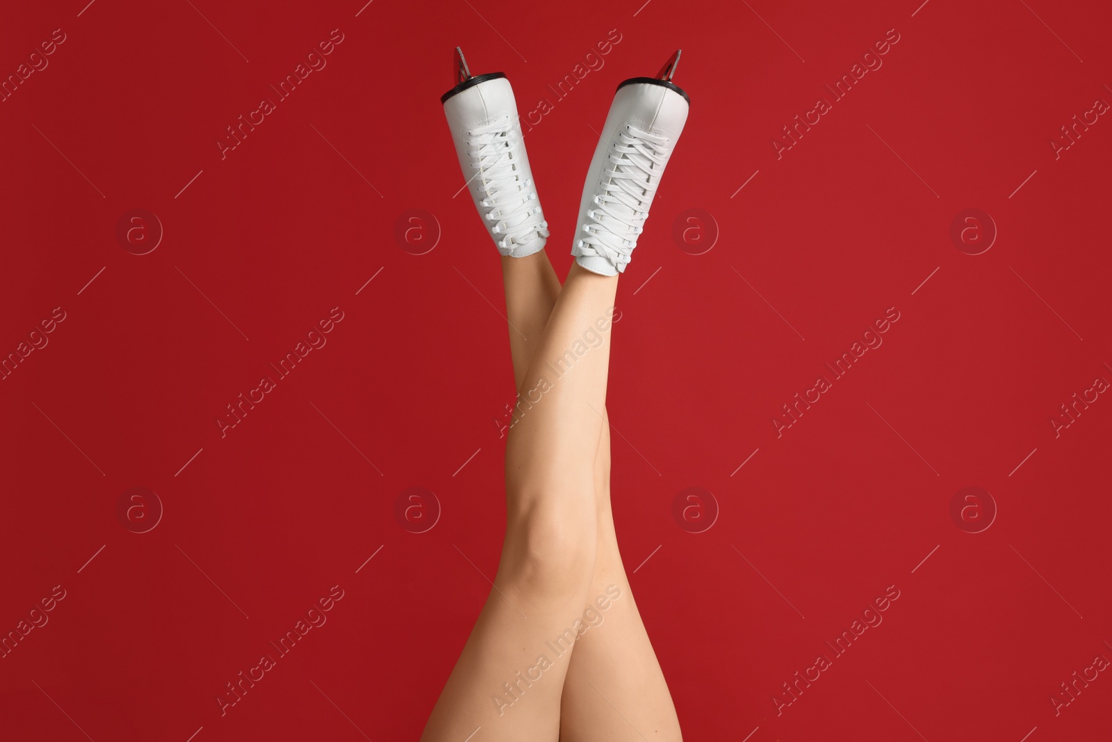 Woman in elegant white ice skates on red background, closeup of legs Photo of Woman in elegant white ice skates on red background, closeup of legs