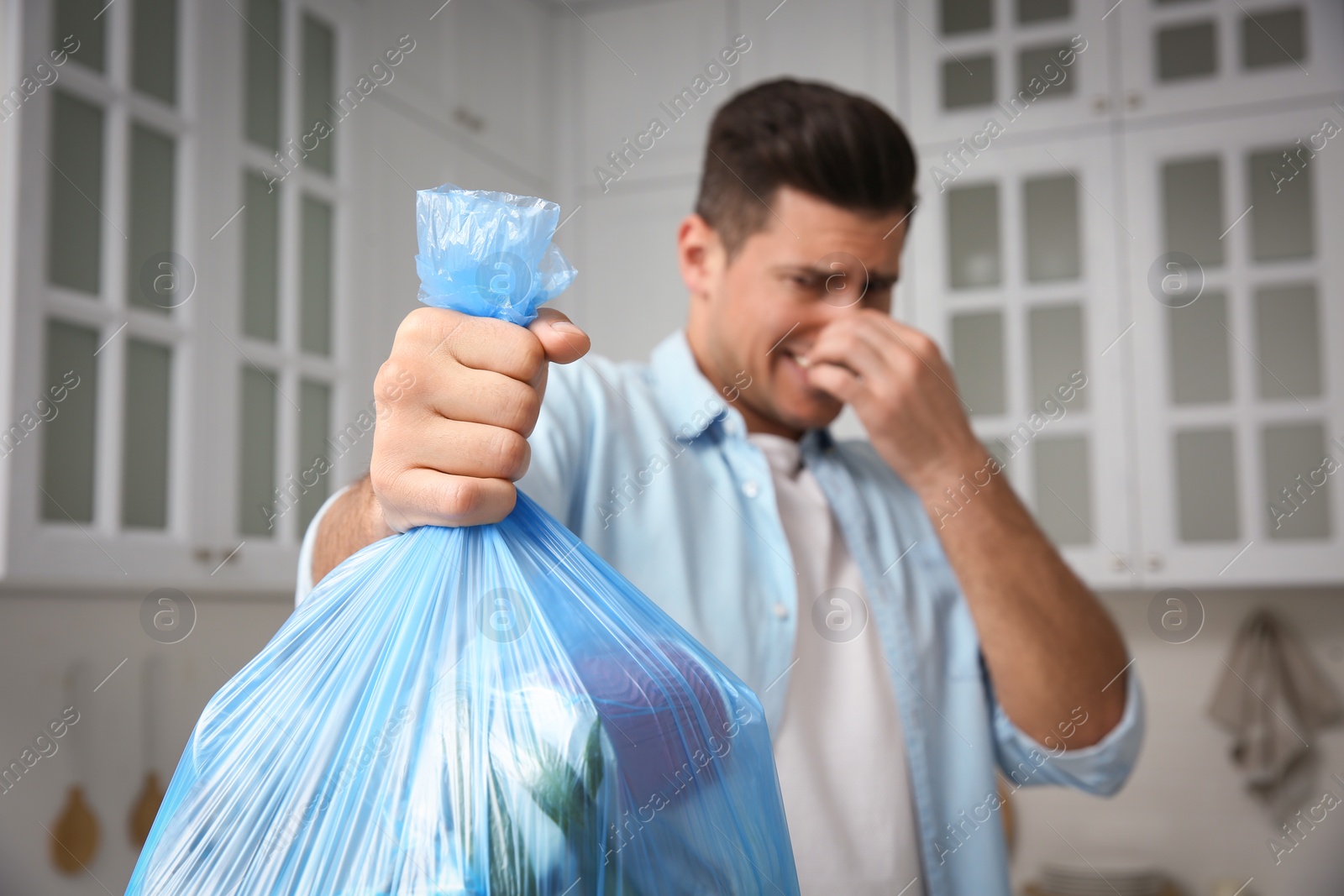 Photo of Man holding full garbage bag at home, focus on hand
