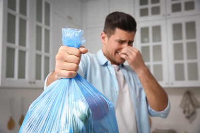 Man holding full garbage bag at home, focus on hand Photo of Man holding full garbage bag at home, focus on hand